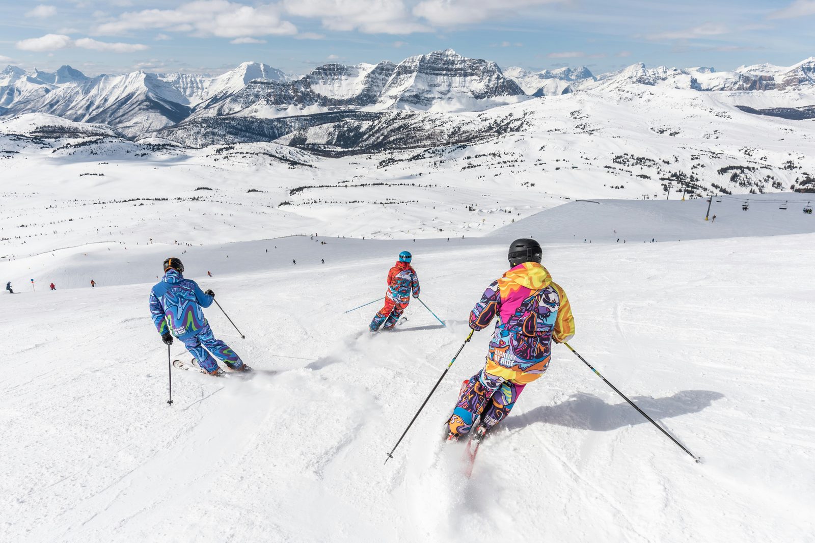 A group of skiers carving down a wide sunny run together